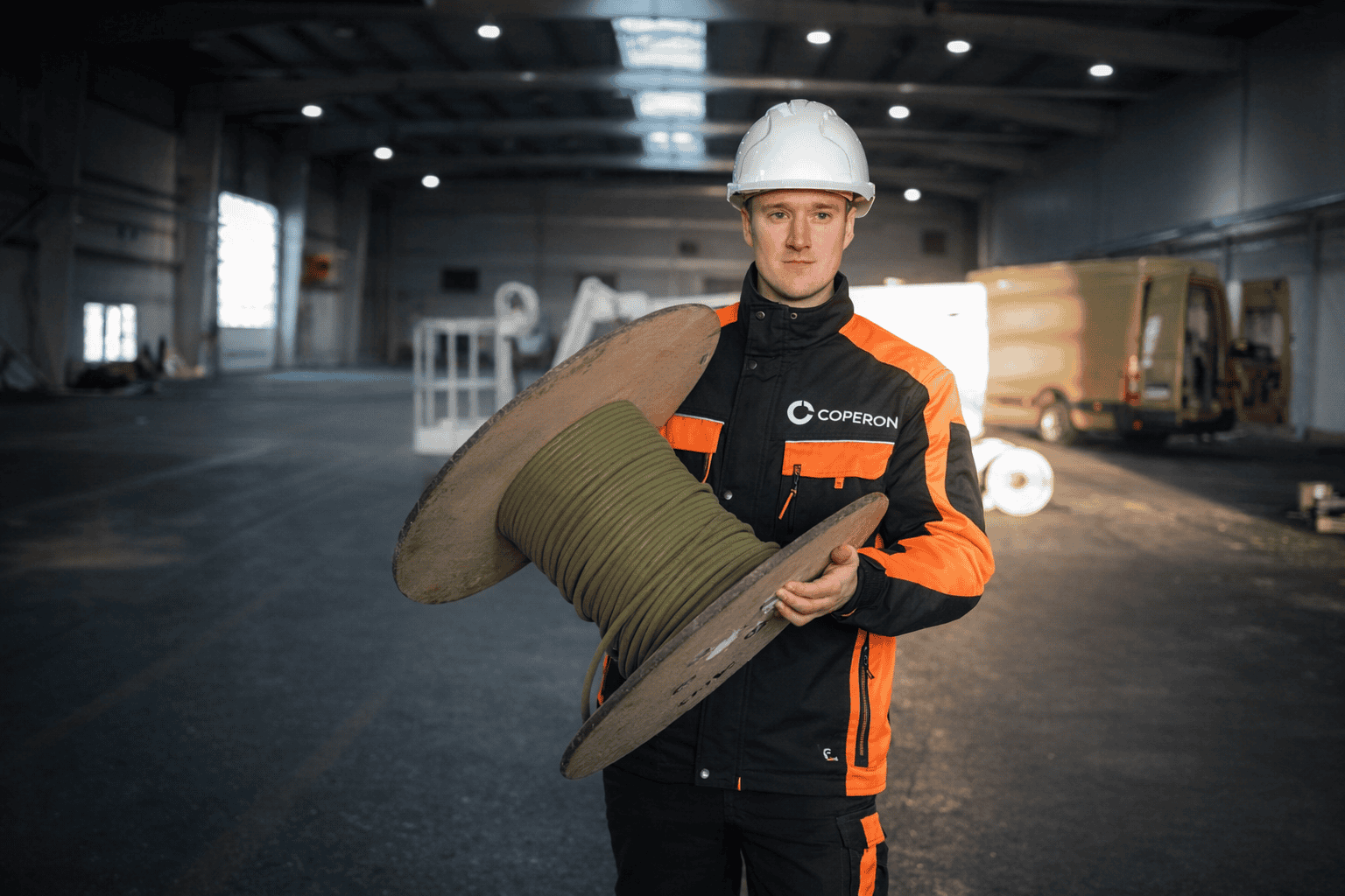 Pracovník v priemyselnom prostredí drží rolku izolačného materiálu, pripravený na montáž alebo inšta.